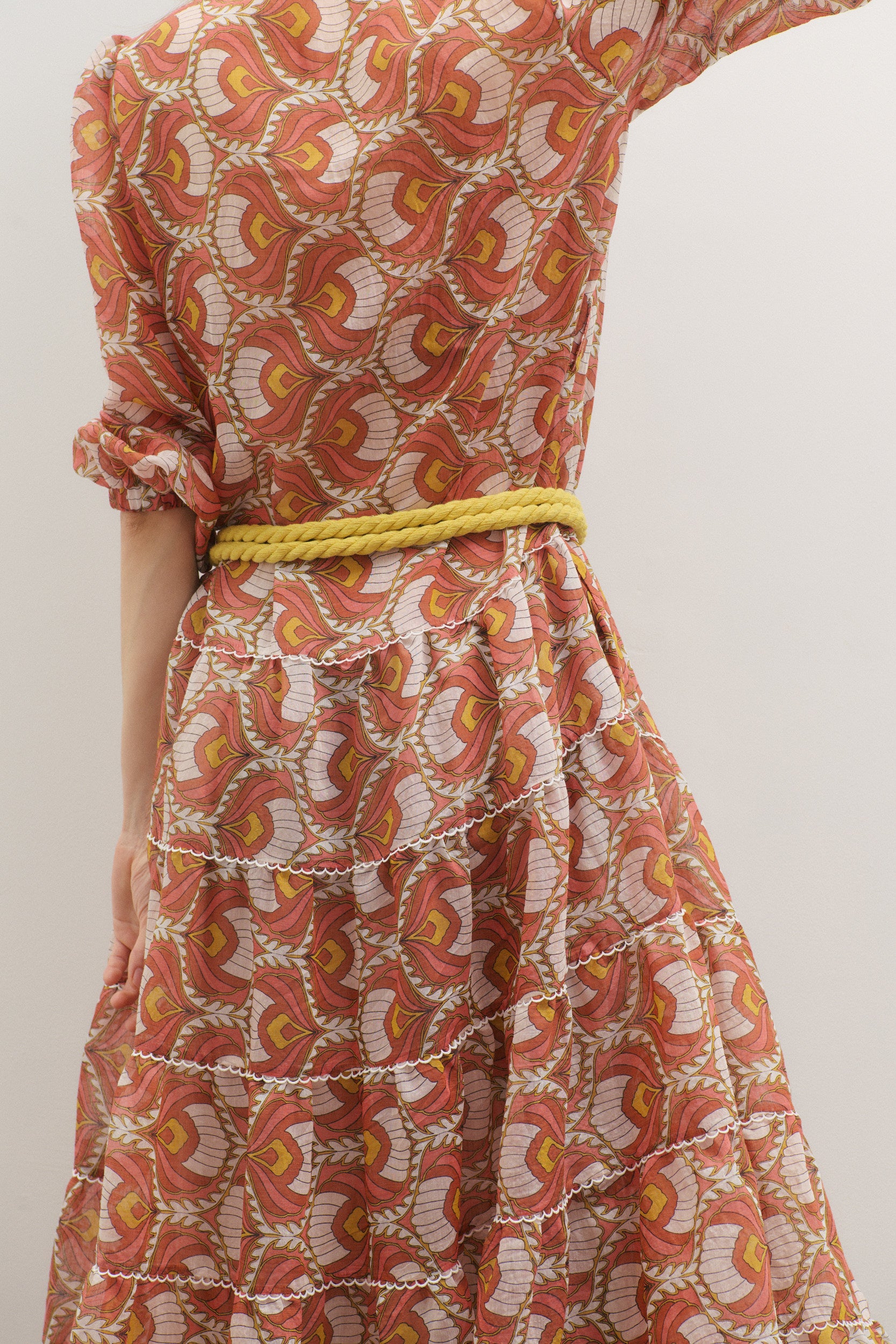 Patterned dress with a yellow belt on a plain background