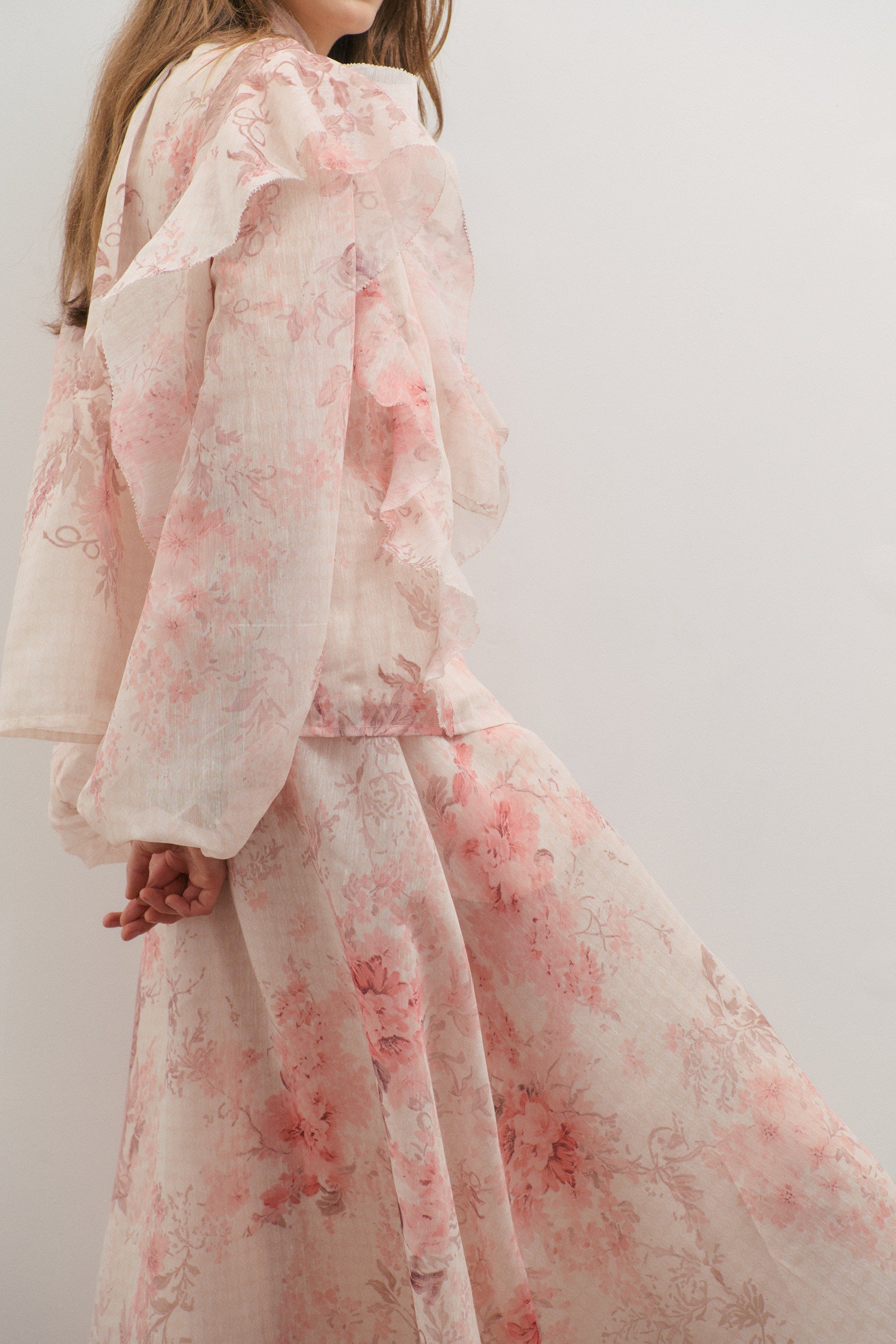 Person wearing a floral top and skirt with a white background