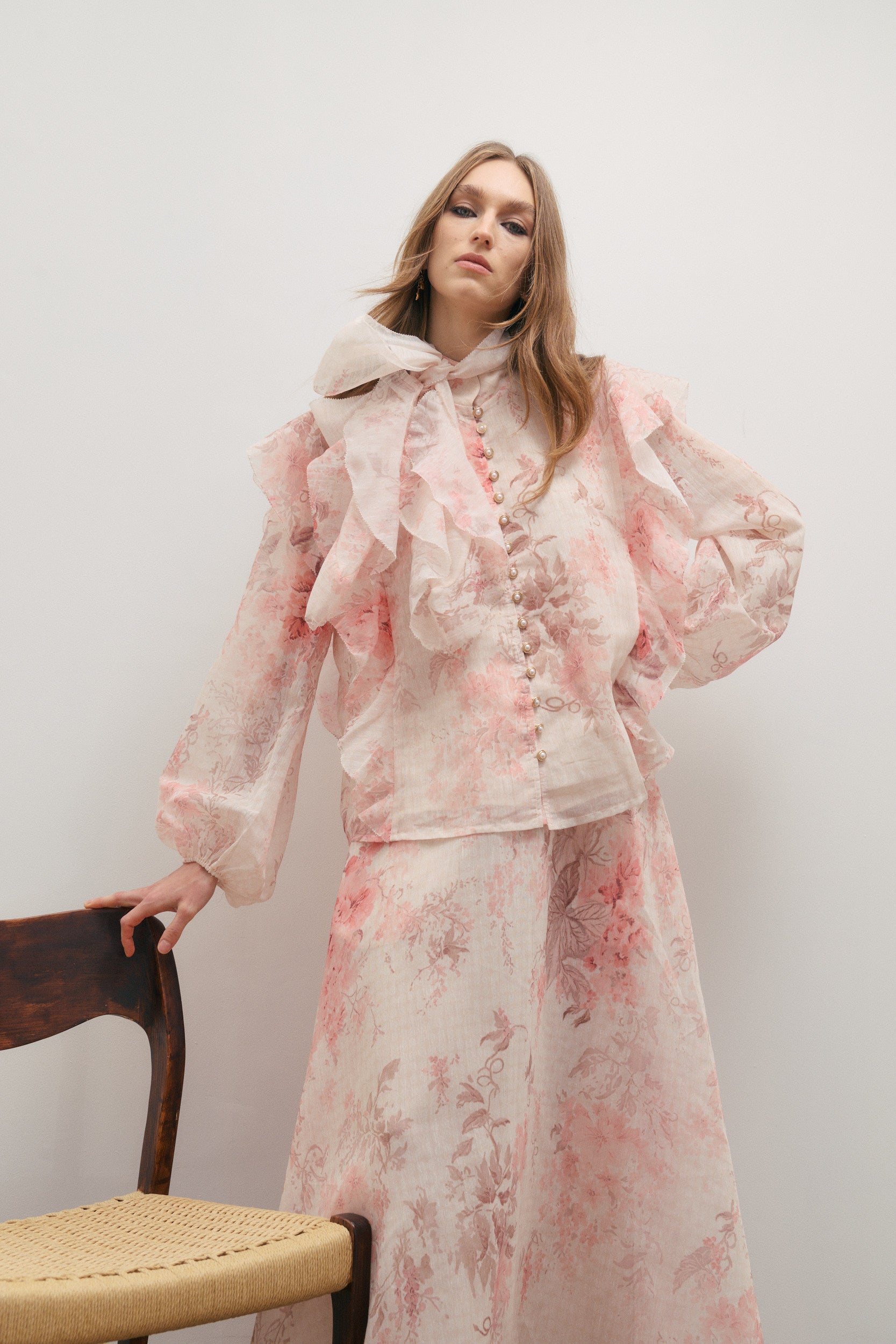 Woman wearing a pink and white floral outfit against a plain background