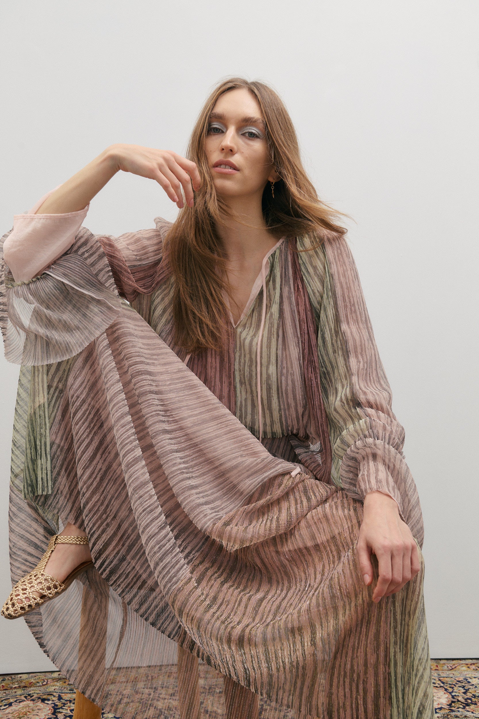 Woman wearing a long, patterned skirt and blouse with a plain background