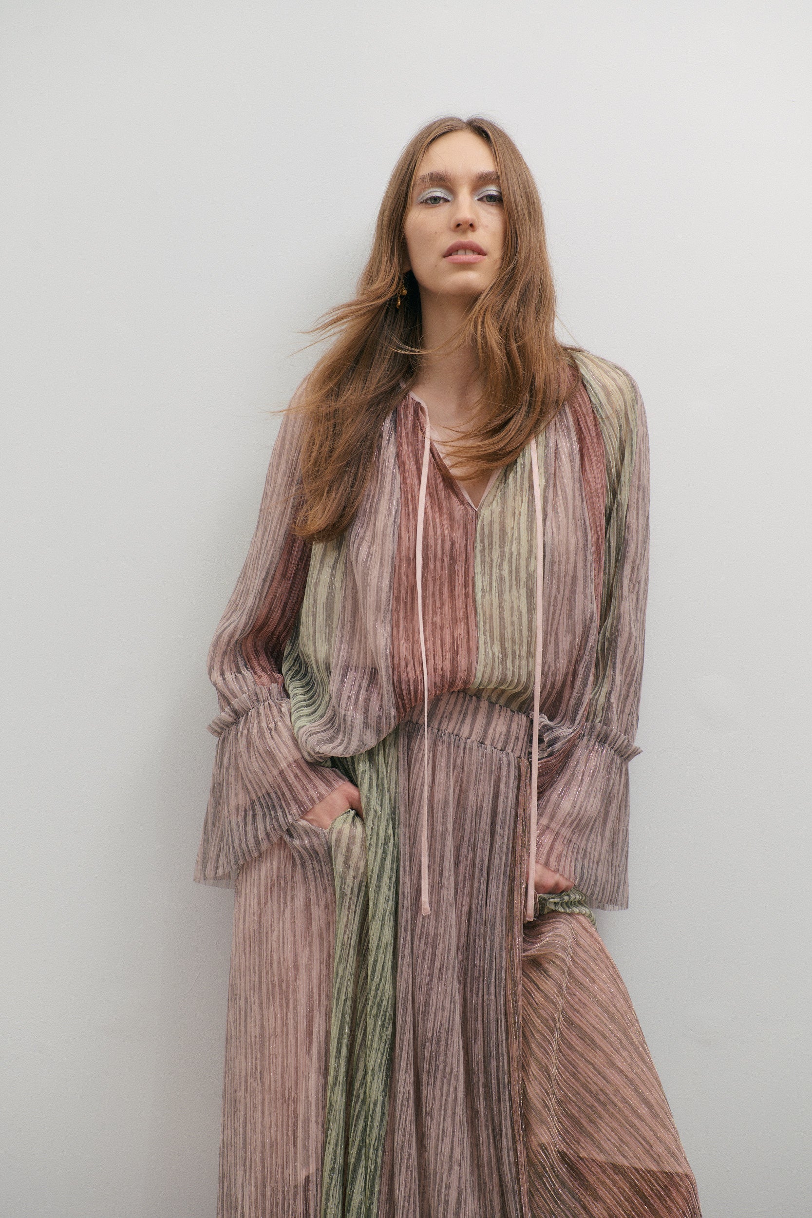 Woman wearing a long, romantic outfit against a plain background