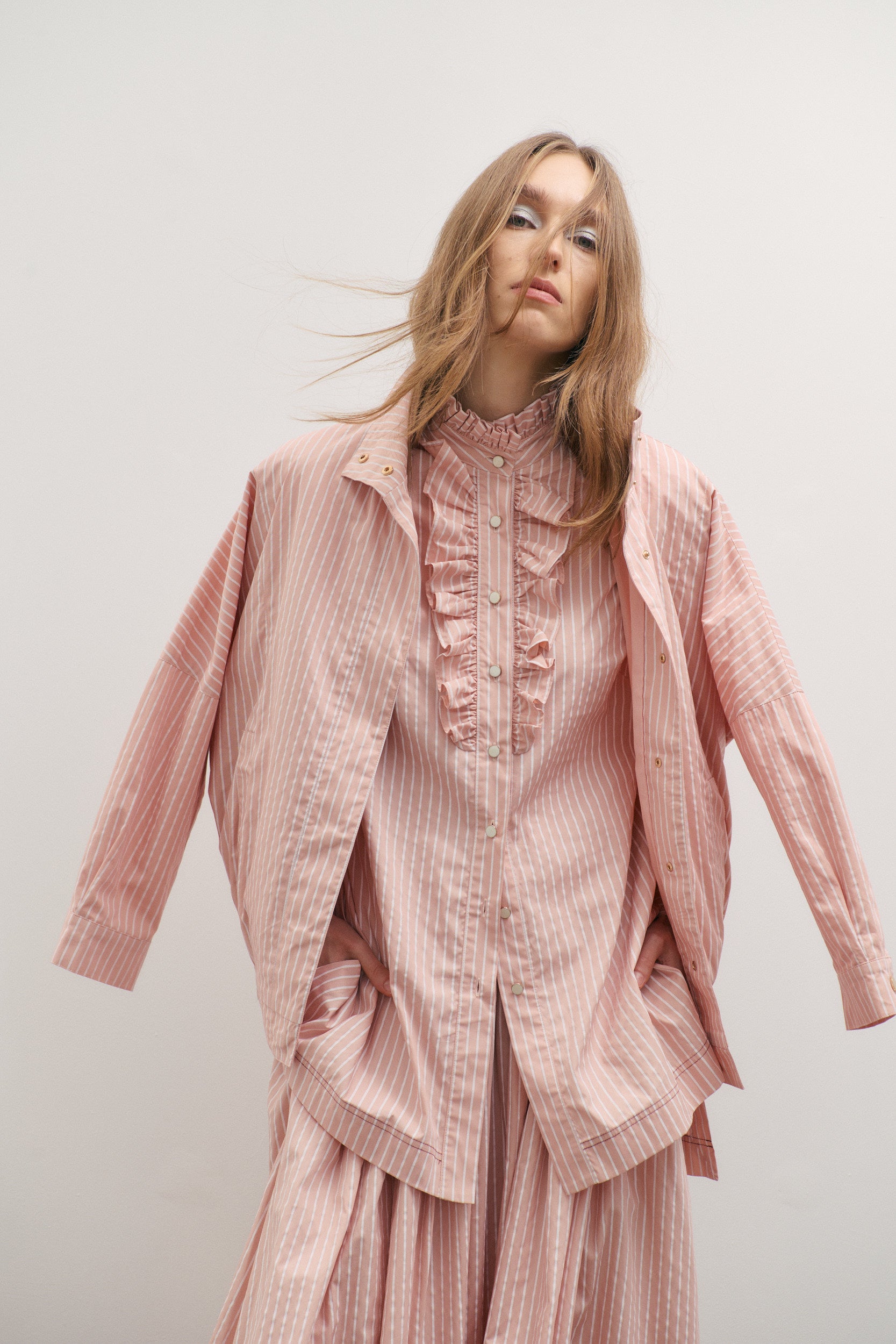Woman wearing a pink striped outfit against a white background