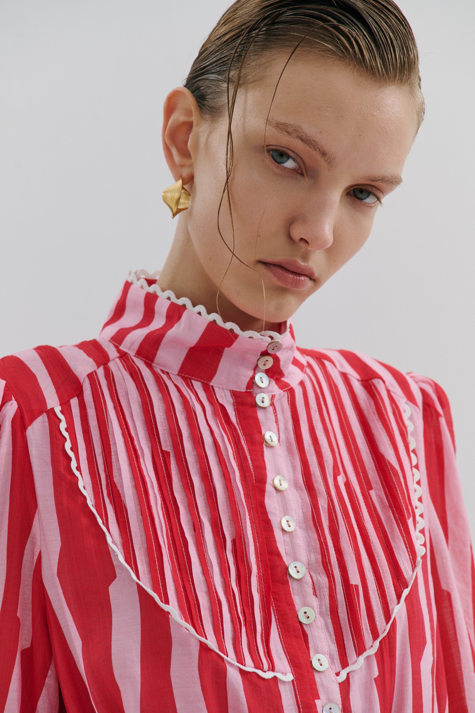 Woman wearing a red and white striped blouse with a plain background