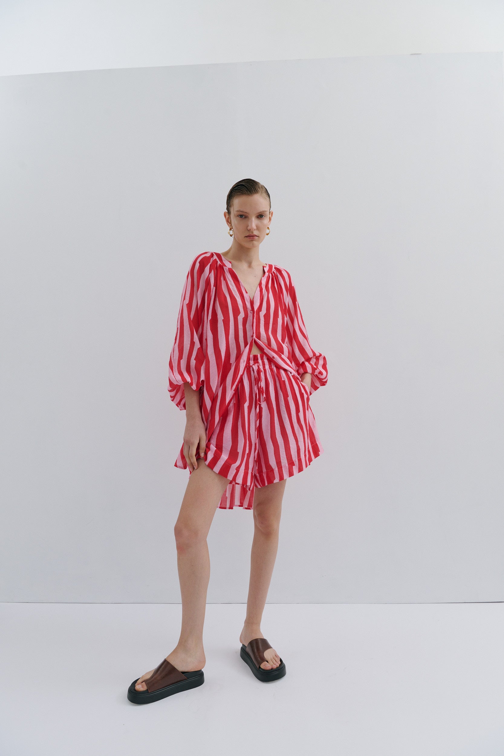 Model wearing a red and pink striped short and shirt on a white background