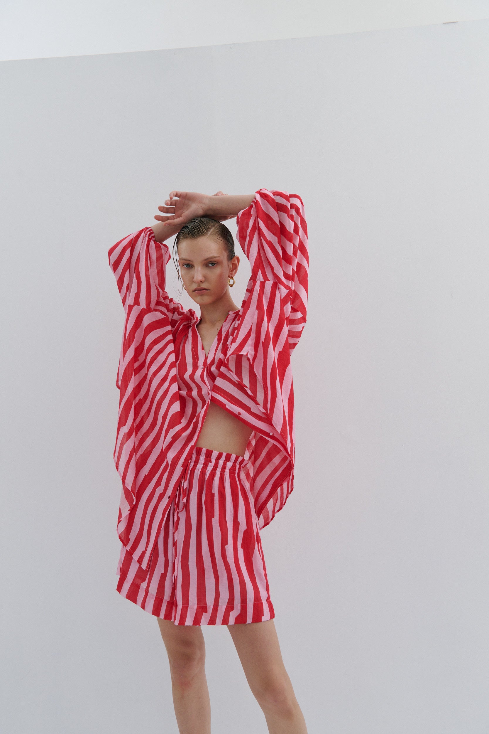 Person wearing a red and pink striped outfit on a plain background