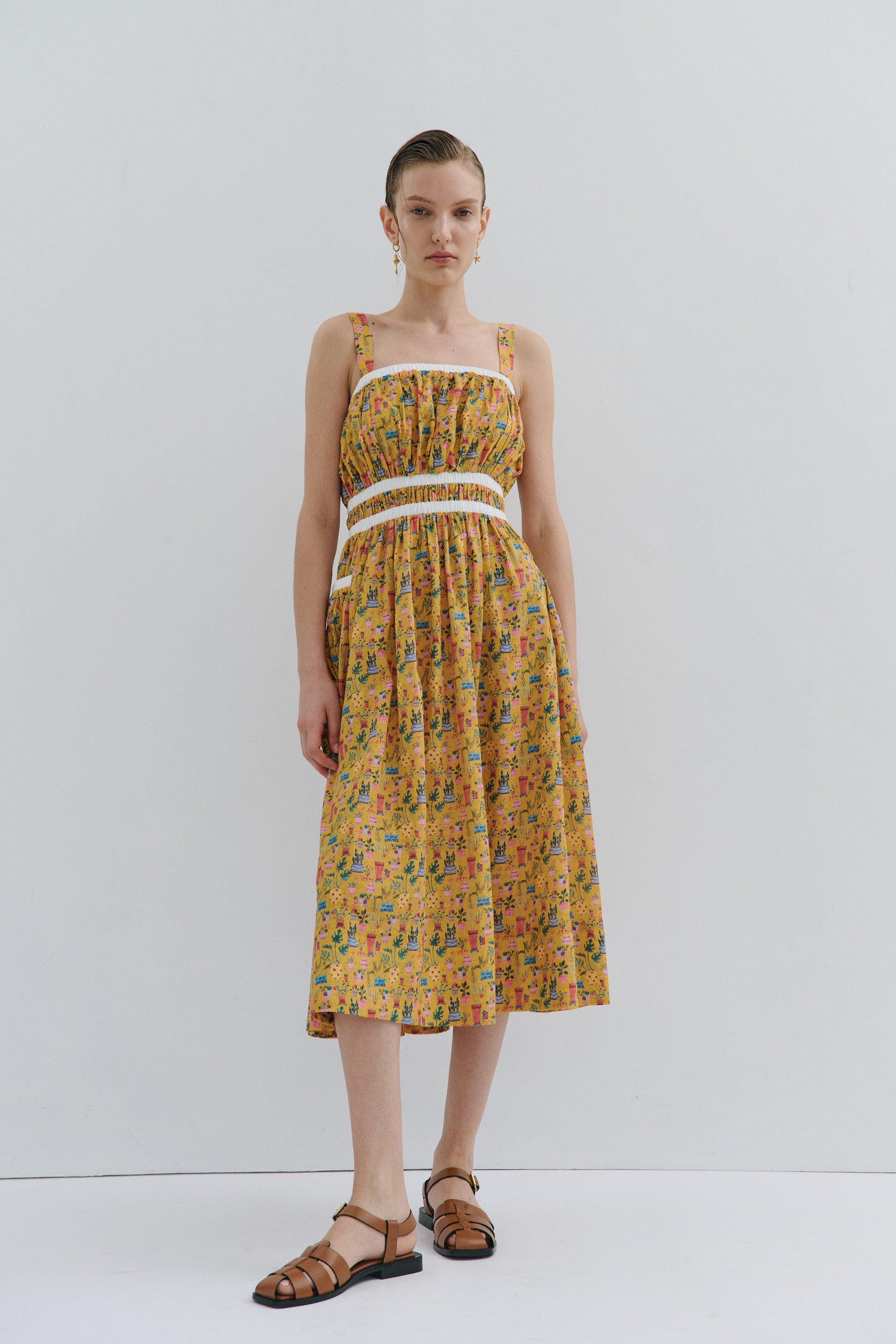 Woman wearing a yellow floral dress on a white background