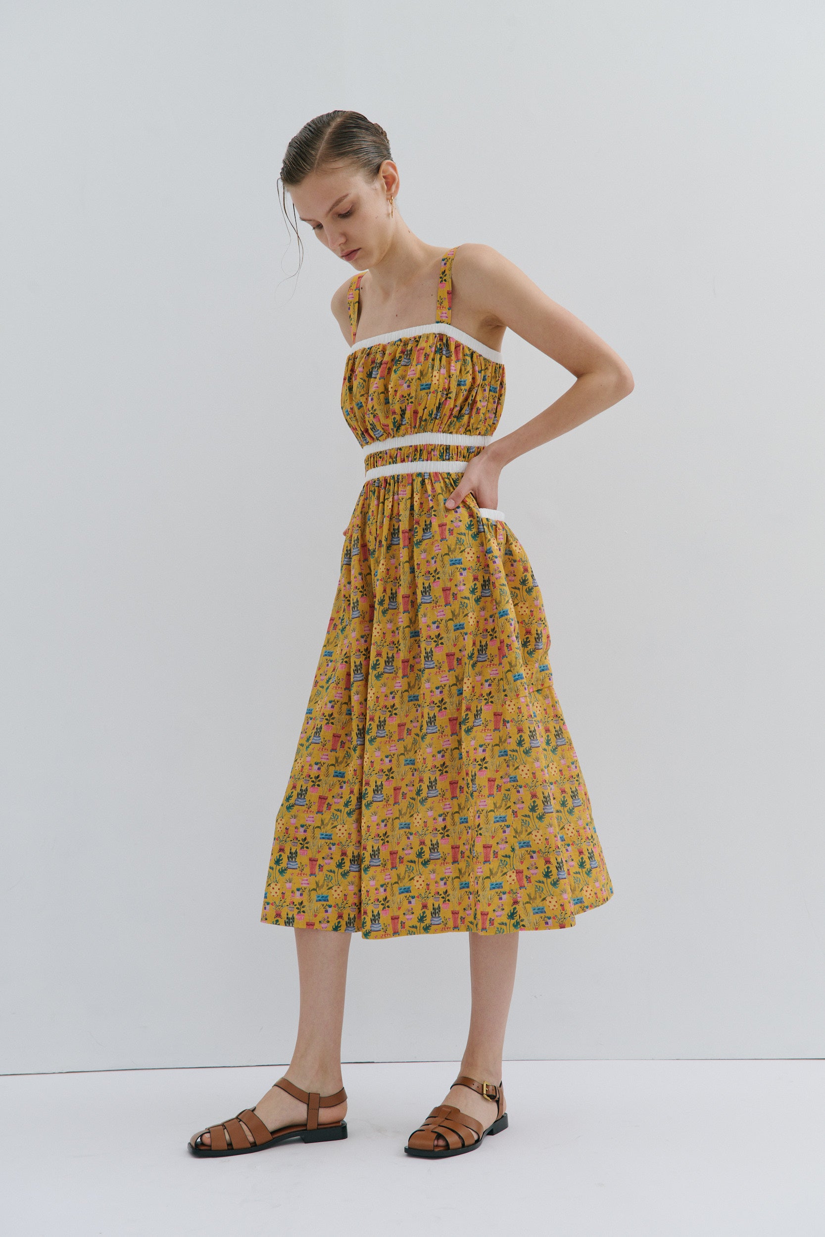 Woman wearing a yellow floral dress on a white background