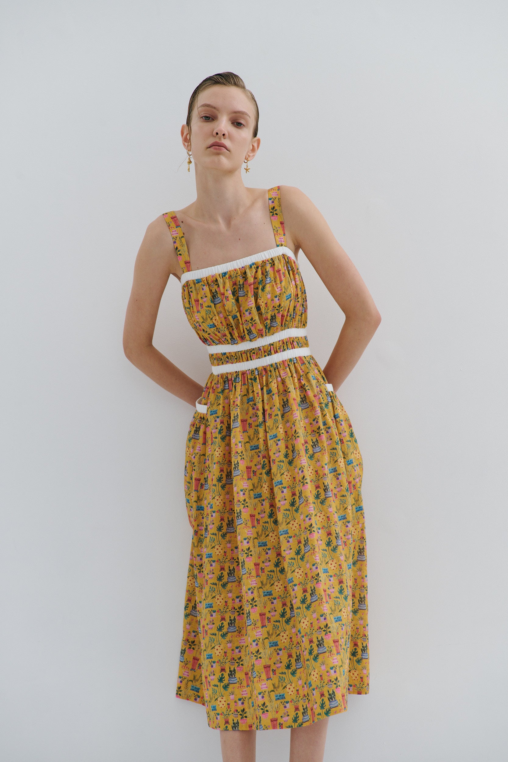 Woman wearing a yellow floral dress against a white background