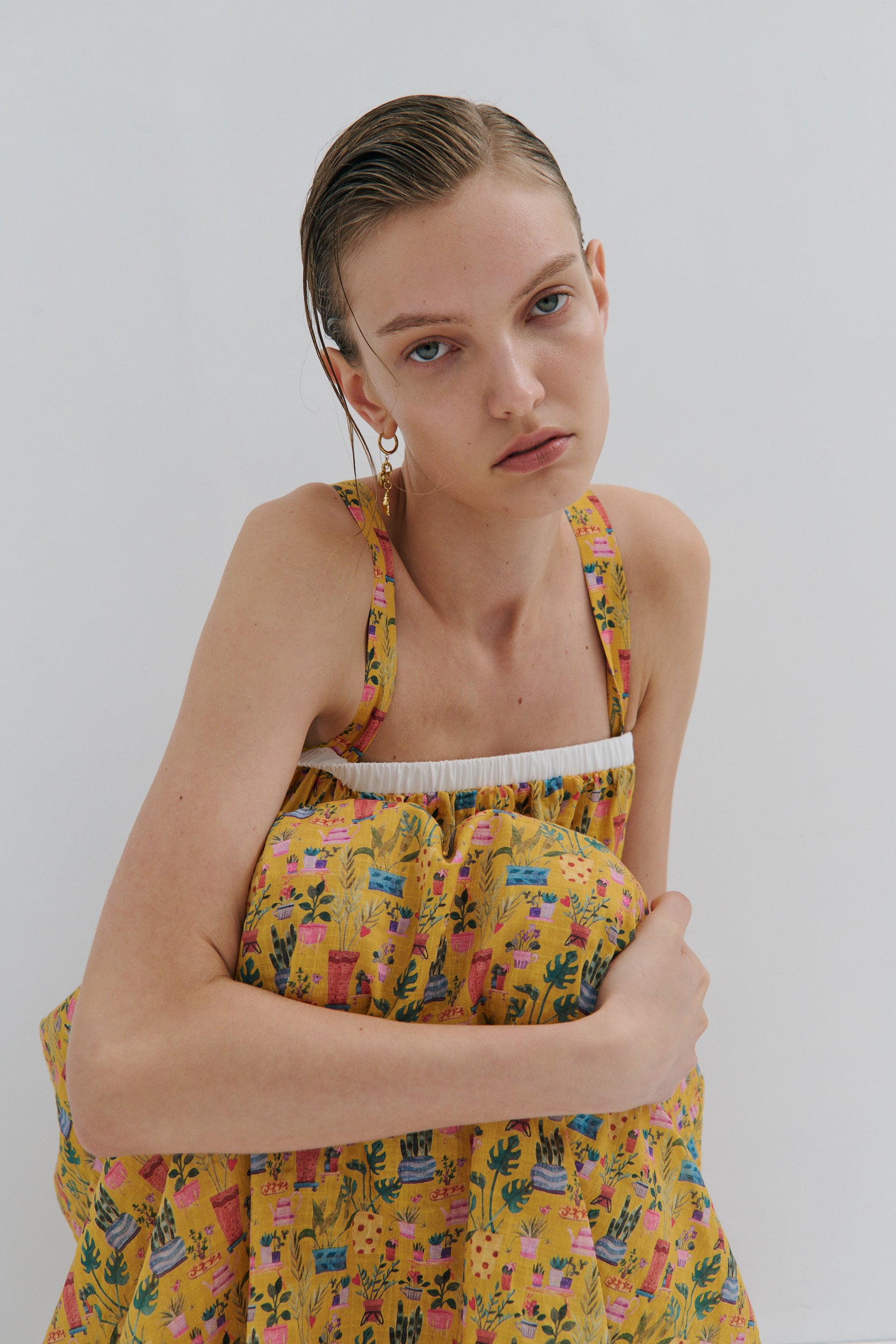 Woman wearing a yellow floral dress against a plain background