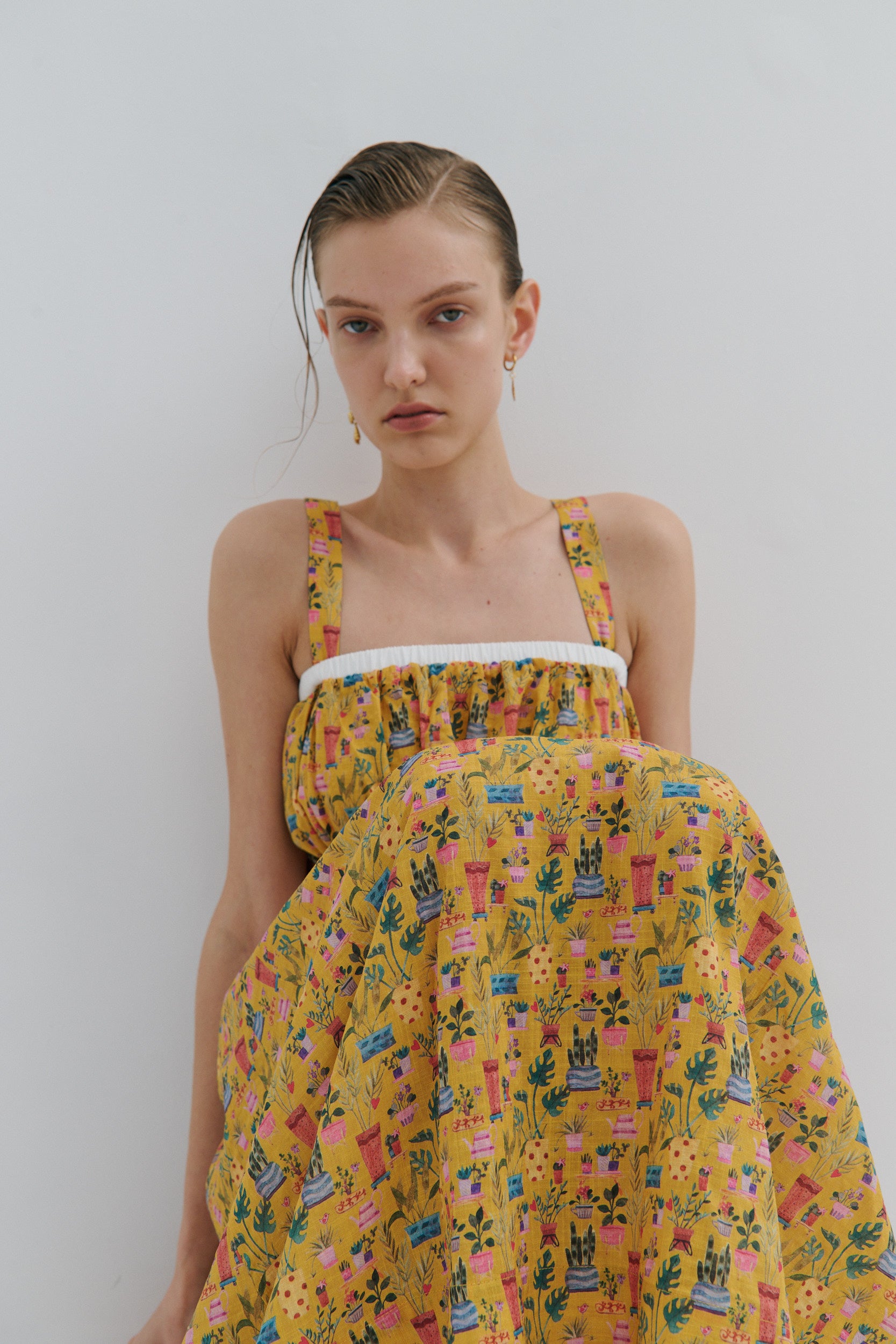 Woman wearing a yellow floral dress against a plain background