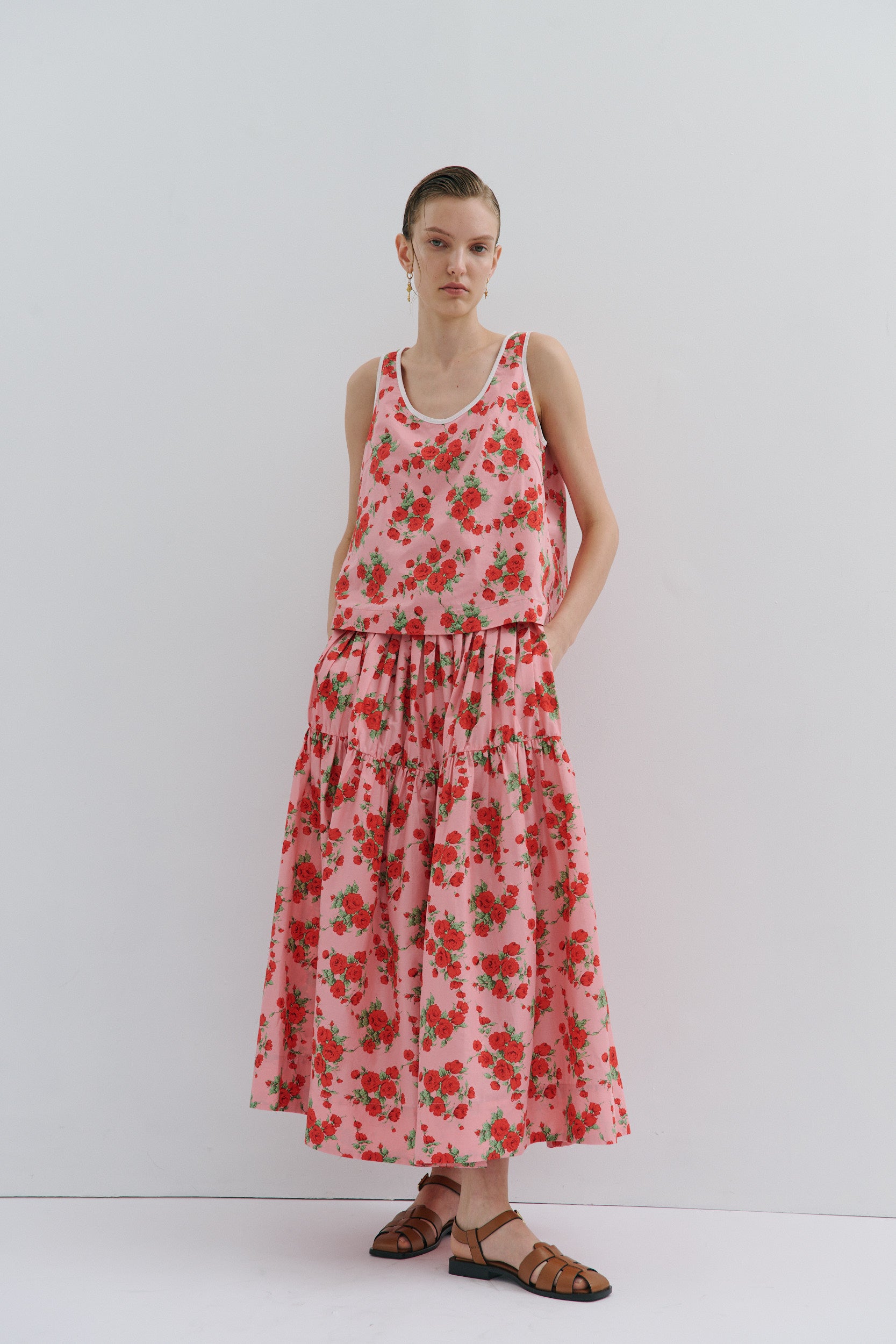 Woman wearing a floral sleeveless top and matching midi skirt on a white background
