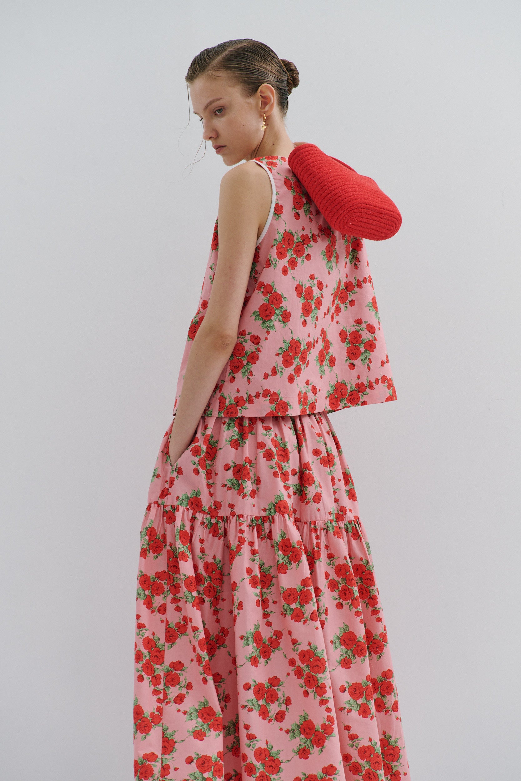 Woman wearing a red floral top and matching skirt on white background