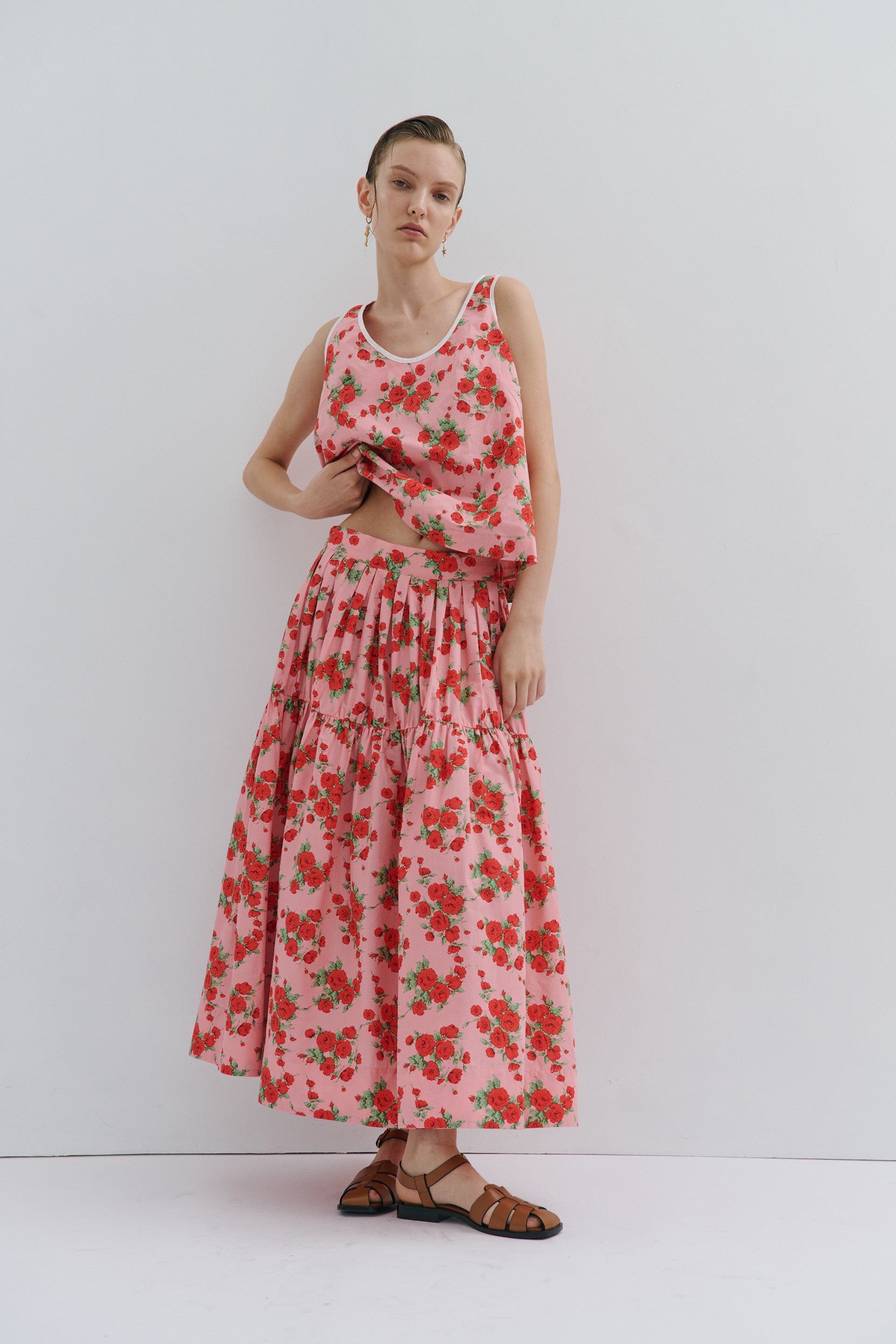 Woman wearing a red floral skirt and top against a white background