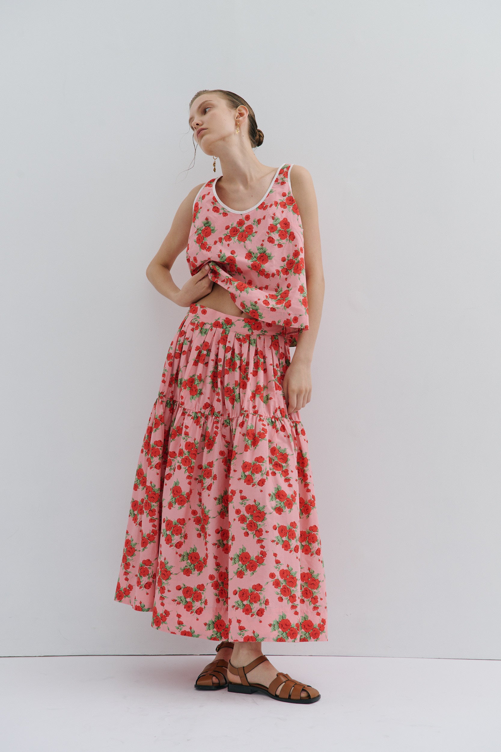 Woman wearing a pink floral skirt and tank top against a white background