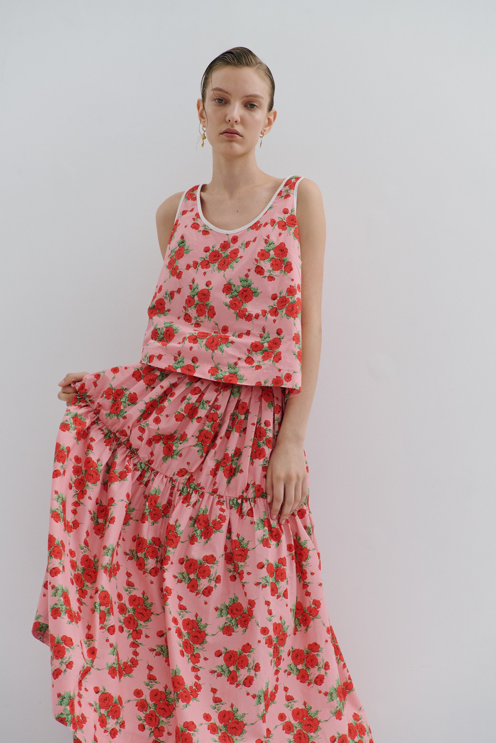Woman wearing a pink floral skirt against a plain background