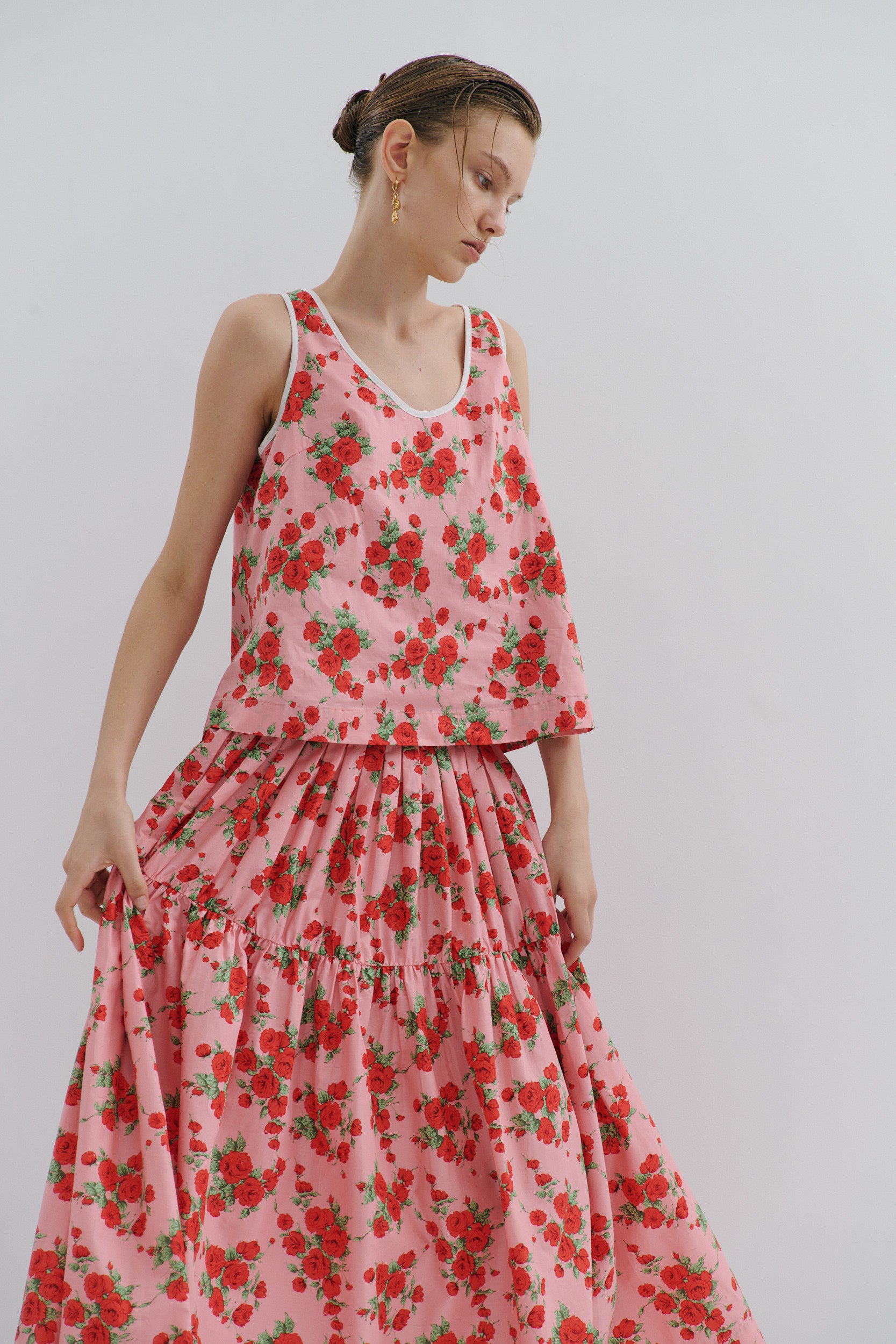 Woman wearing a pink floral top and skirt against a plain background