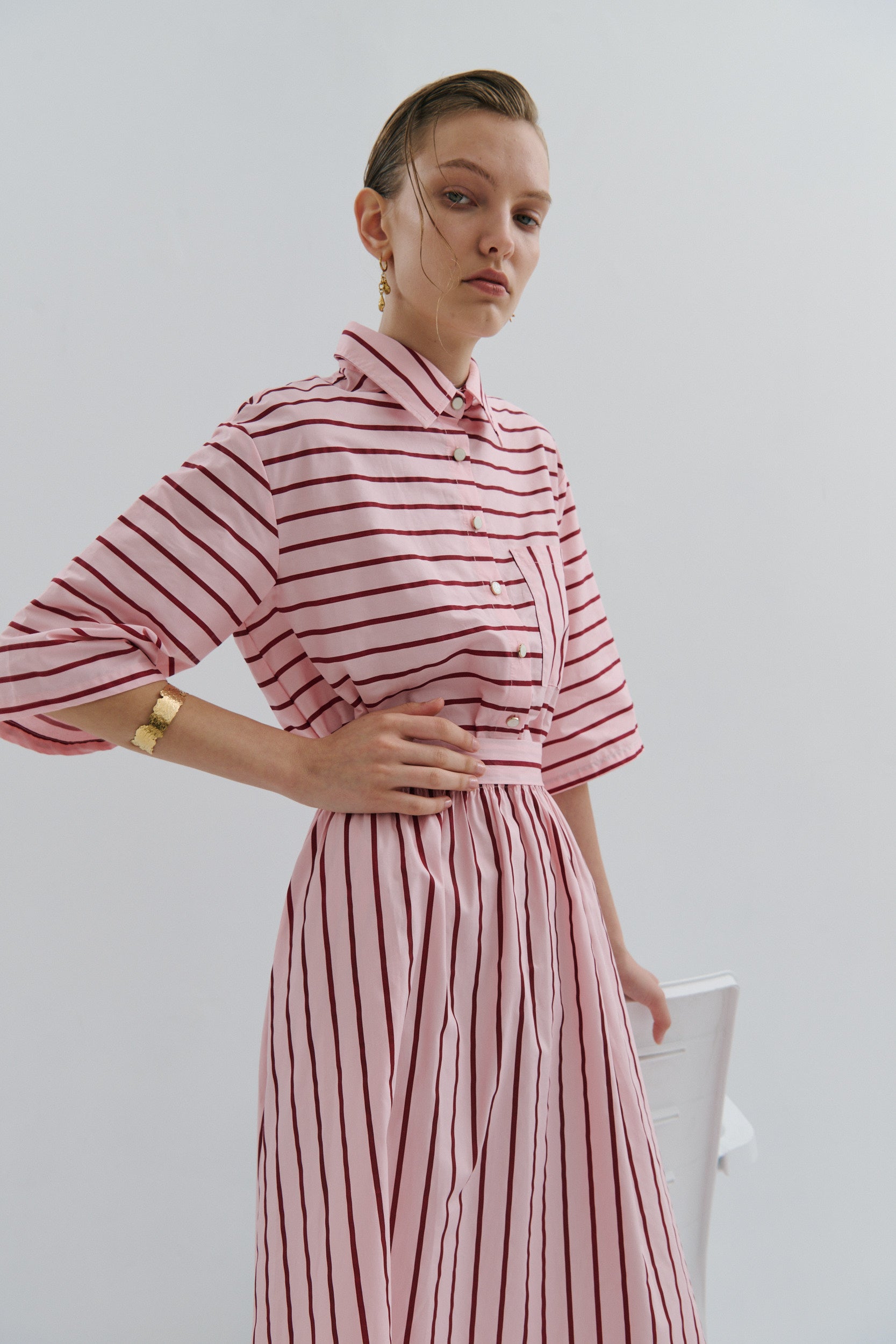 model wearing a pink and red stripe shirt dress, with pearl gold buttons, elbow length sleeves and collar