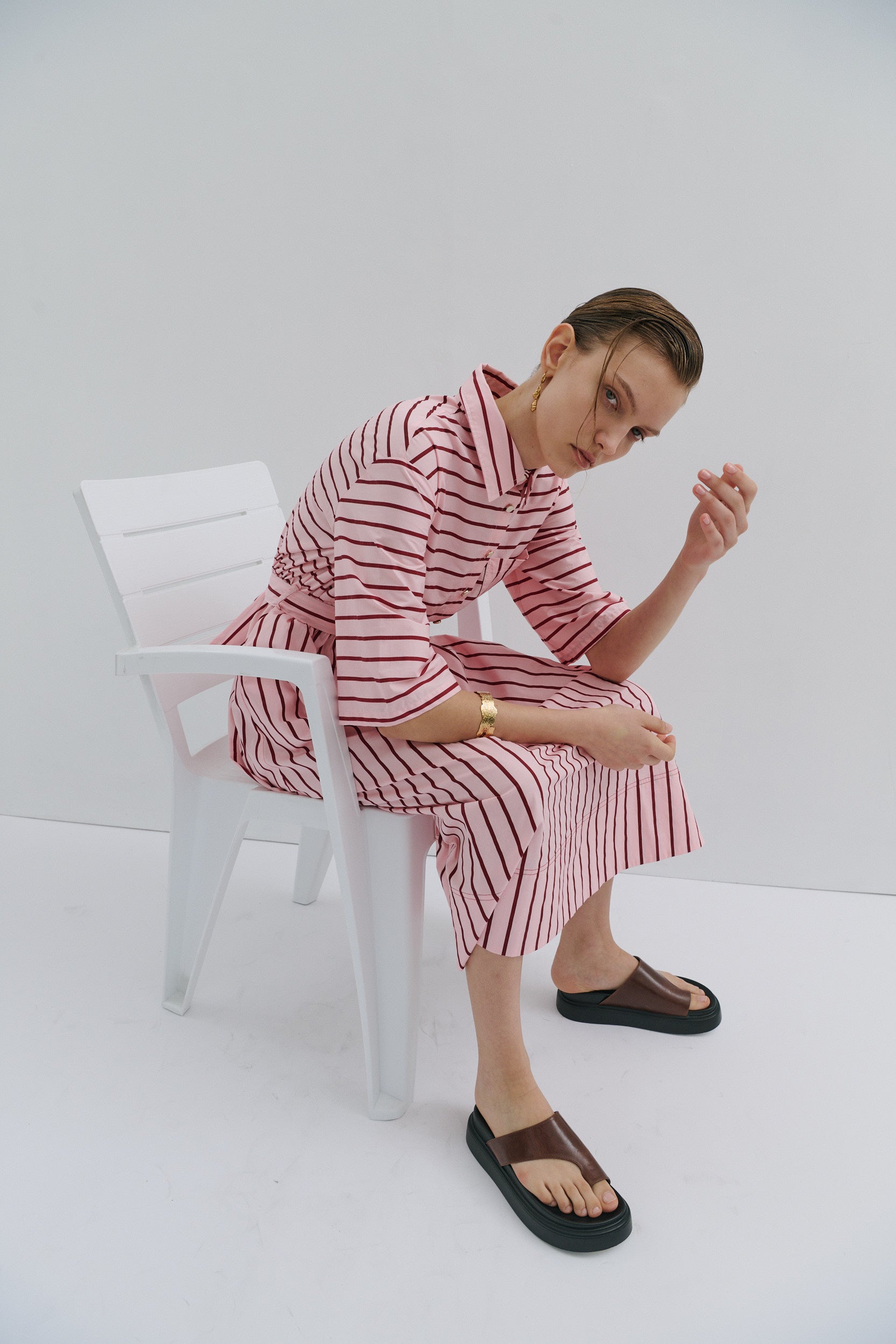 red and pink stripe dress on a woman sitting on a white chair on a white backdrop