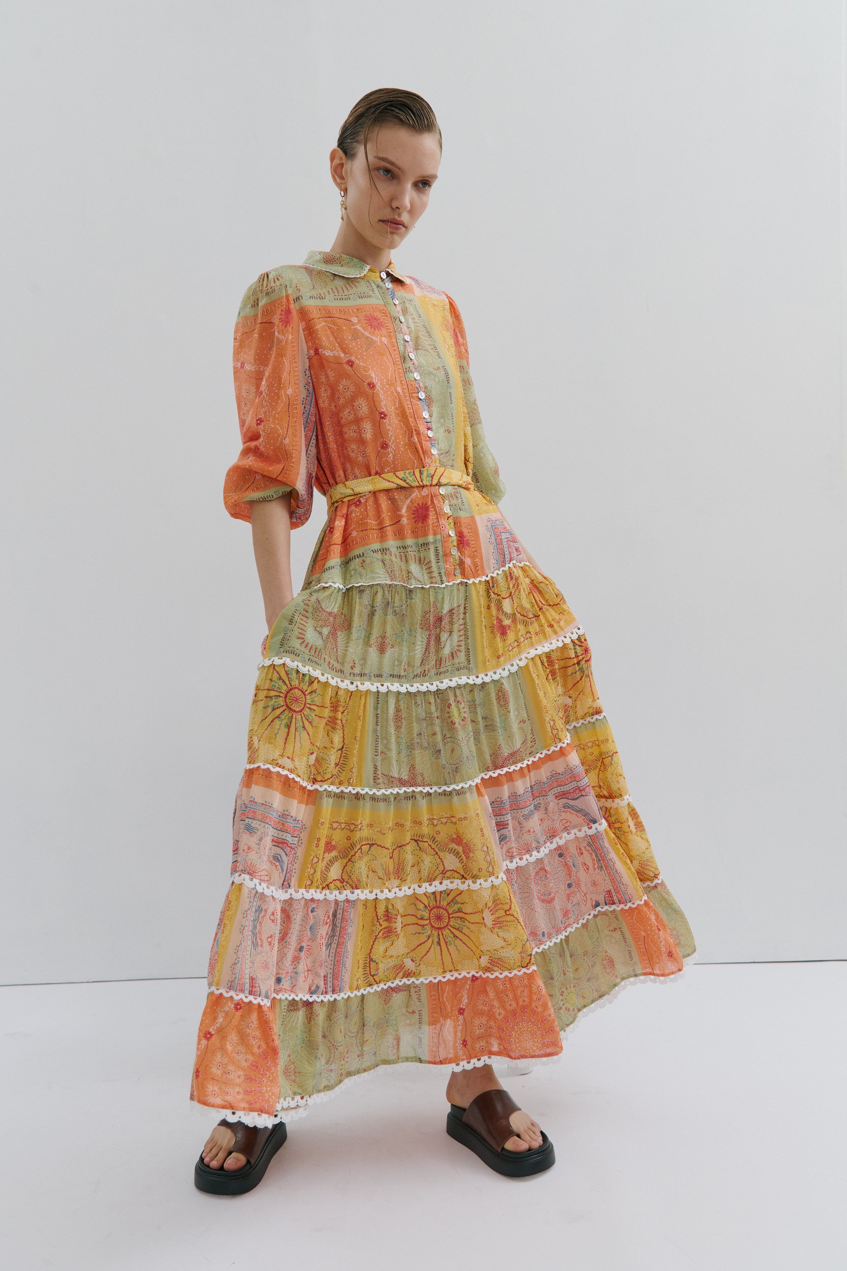 Model wearing a colorful, tiered dress against a white background