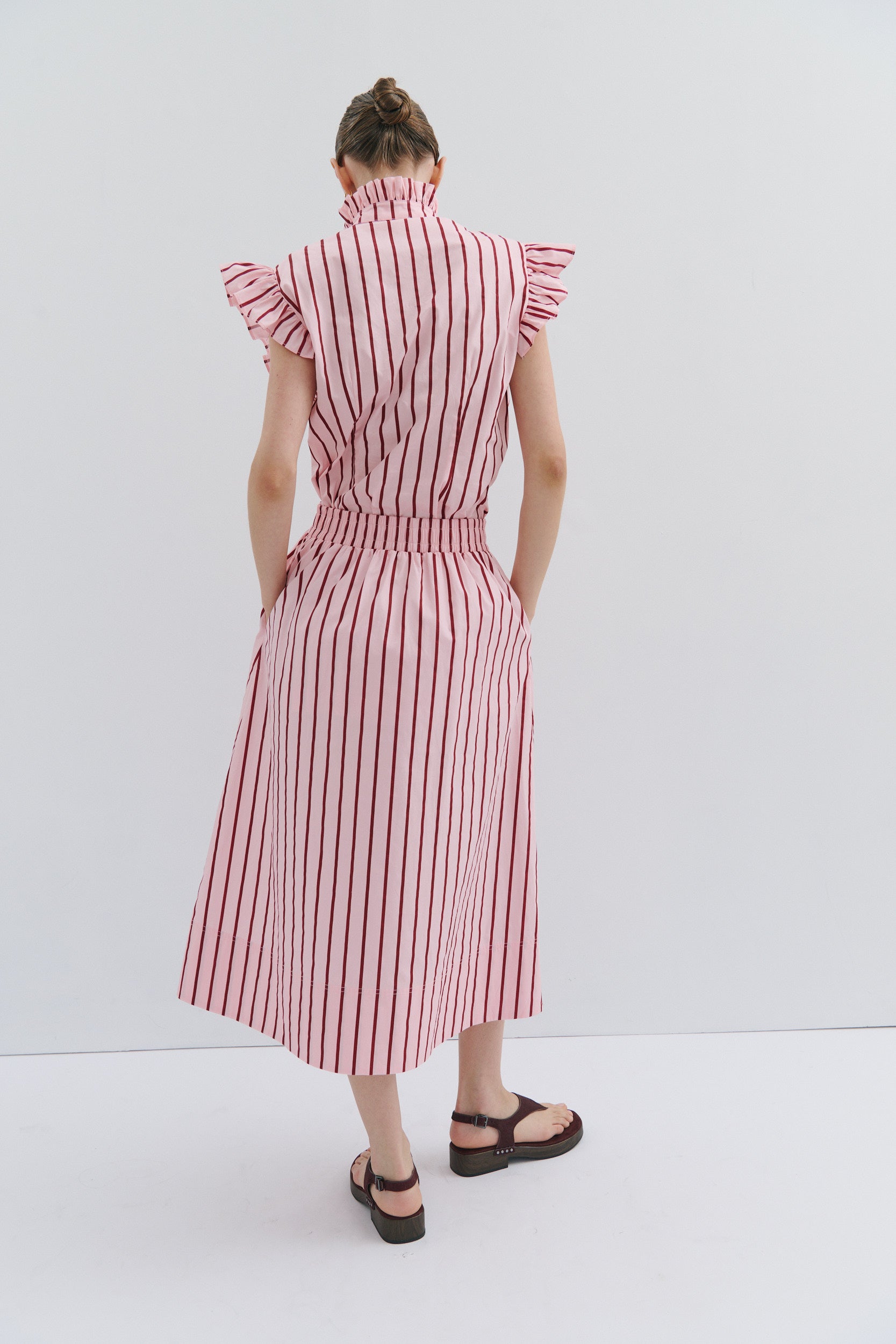 woman wearing a pink and red stripe midi skirt and sleeveless frill shirt by fashion designer Maevarii