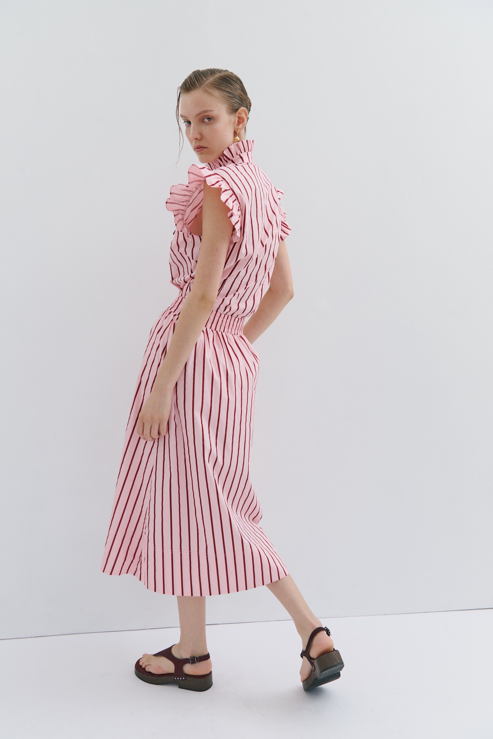 woman wearing the Mad Hatters Frill shirt and matching midi skirt in a cotton poplin red and pink stripe