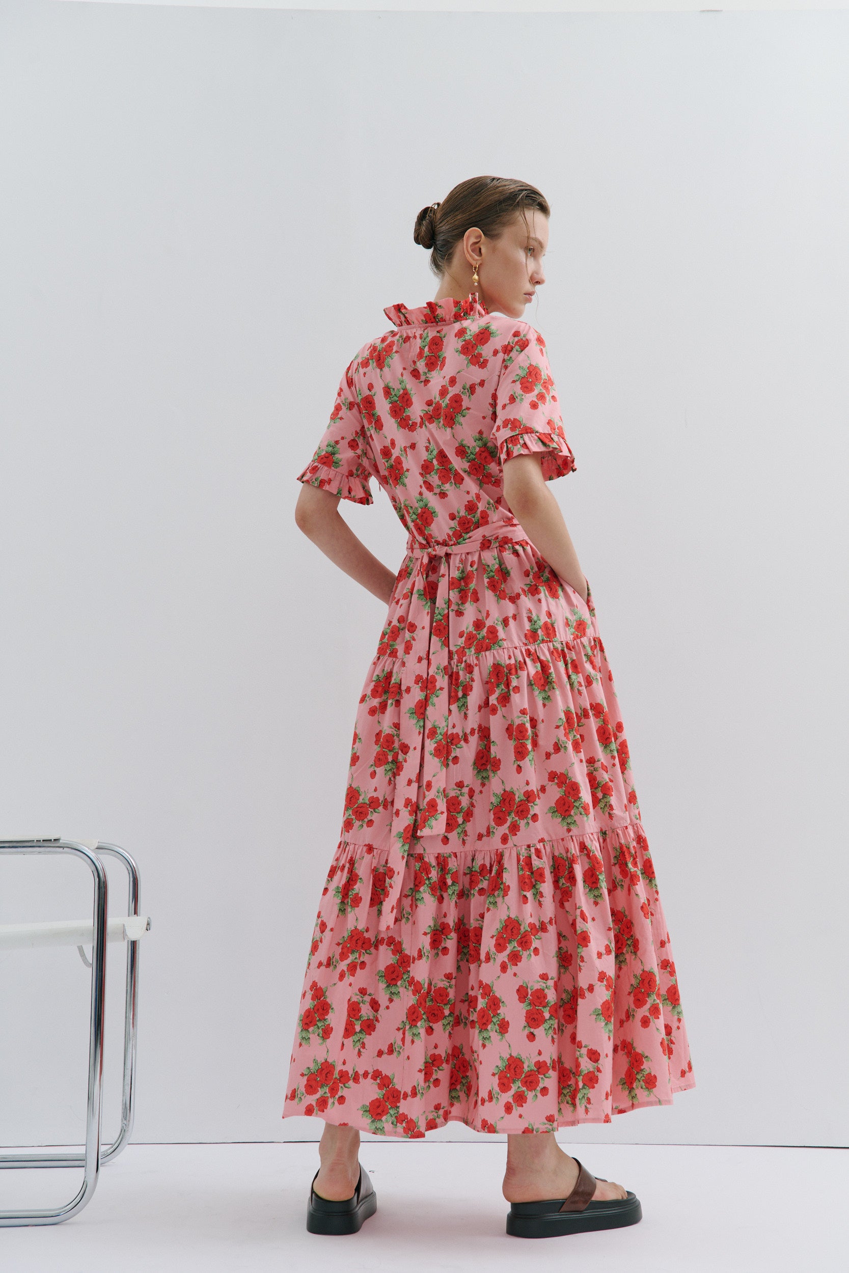 Woman wearing a red floral dress standing against a white background