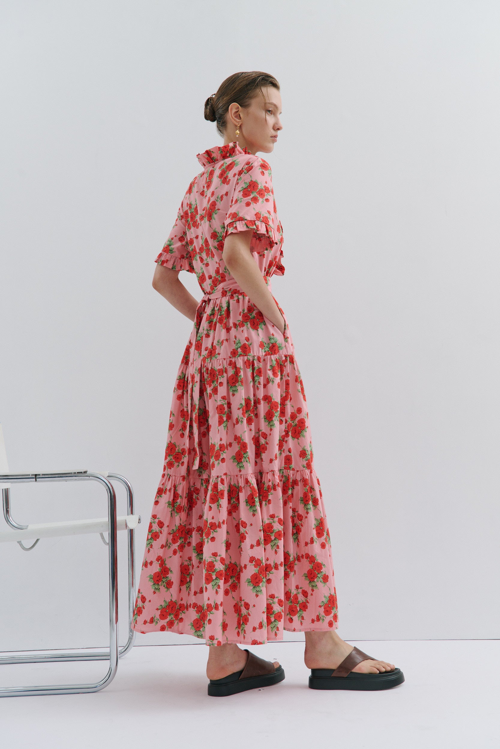 Woman wearing a red floral dress standing against a white background