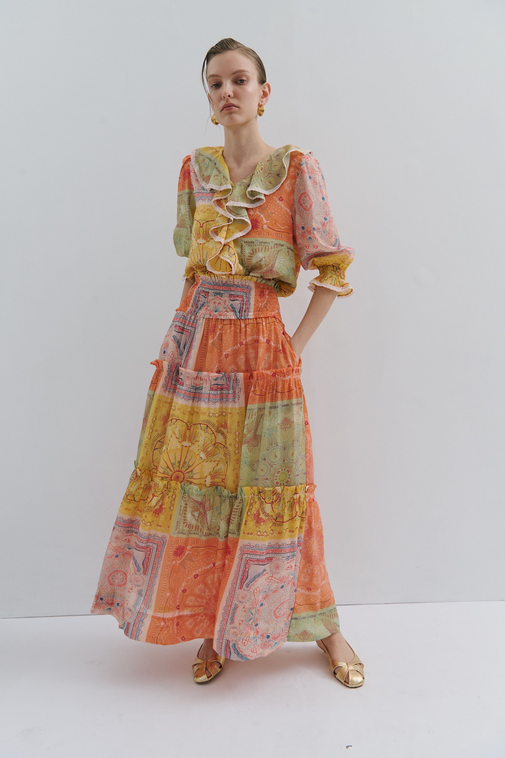 Model wearing a colorful patchwork skirt and top with a white background