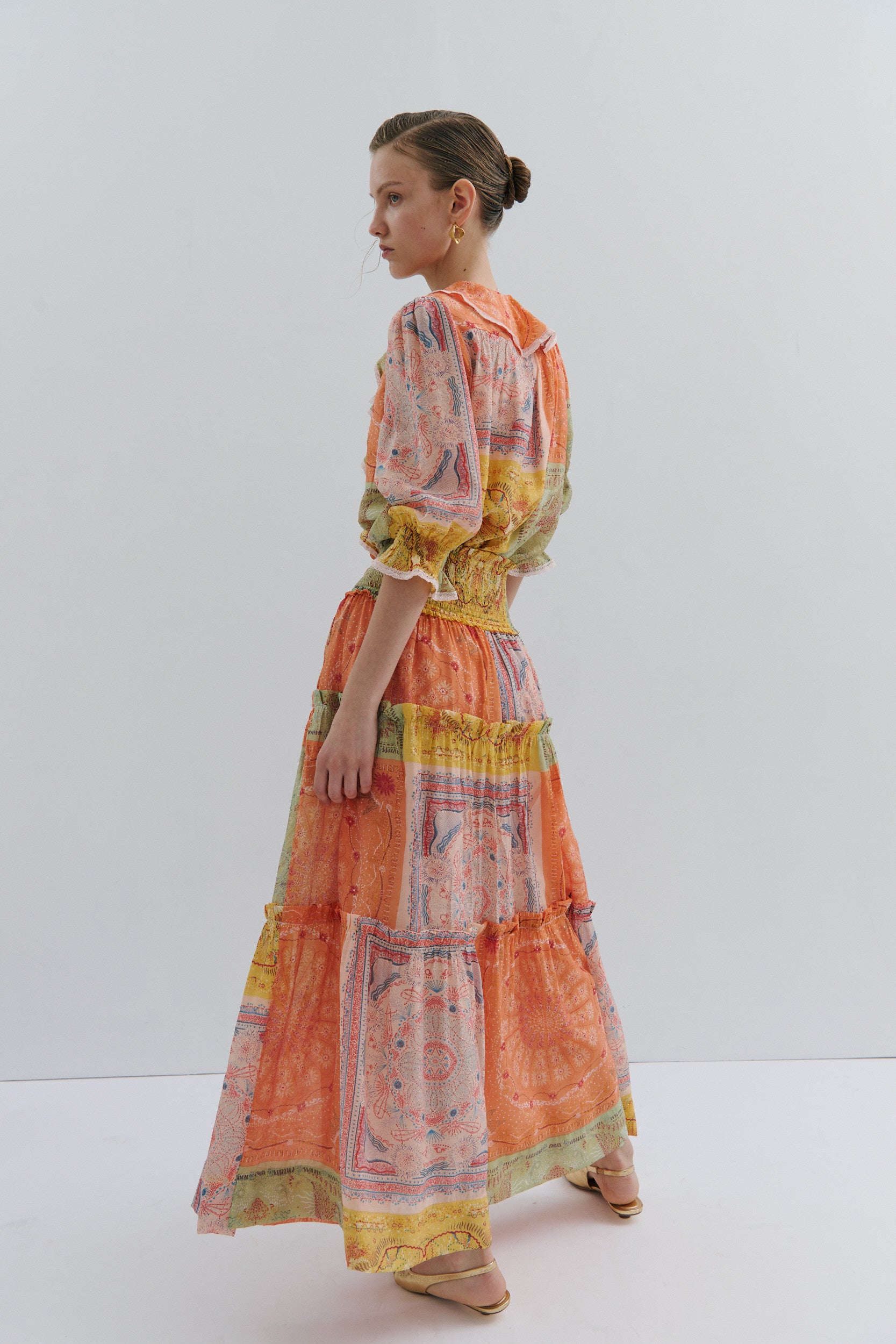 Woman wearing a colorful maxi skirt and blouse with a white background