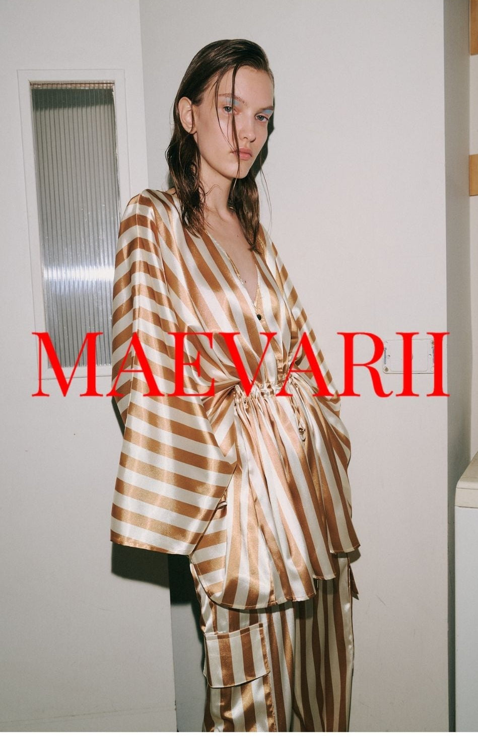 Woman wearing a gold striped kimono style jacket and cargo pants with drawstring cuff, with 'MAEVARII' branding in red text.