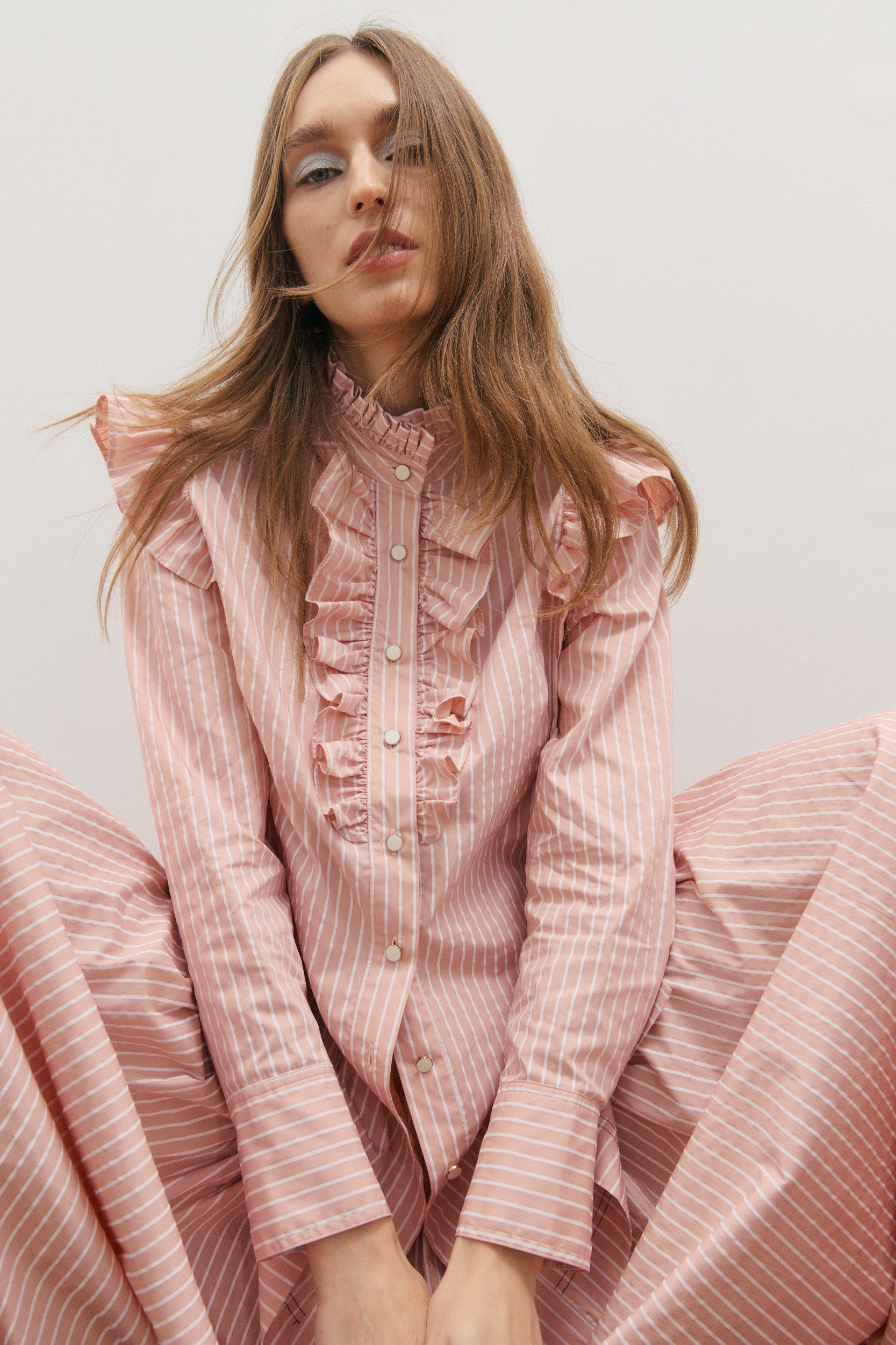 Woman wearing a pink ruffled shirt against a plain background